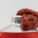 Tomatenmark quillt aus einer Tube. Die lange Tomatenmark haltbarkeit macht es zu einem praktischen Küchenhelfer.