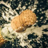Champagnerkorken spritzt aus der Flasche, ein Moment des Feierns, der zeigt, wie wichtig es ist, Champagner richtig zu lagern.