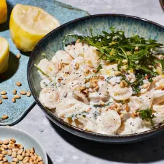 Cremige Ricotta Zitronen Pasta mit Pinienkernen und Rucola, garniert mit frischer Zitronenschale.