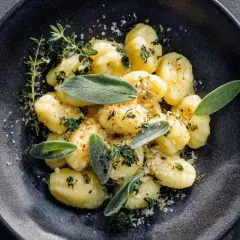 Gnocchi mit Salbeibutter, garniert mit frischen Kräutern und Parmesan. Ein köstliches Gericht, das nach Italien schmeckt.