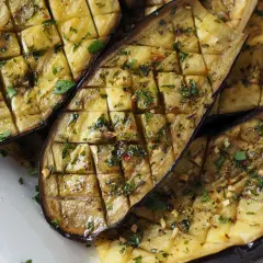 Ganze Aubergine im Ofen, in Scheiben geschnitten und mit Kräutern und Gewürzen verfeinert, bereit zum Genuss.