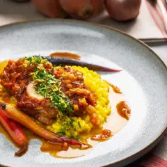 Ein köstliches Ossobuco Rezept mit zartem Kalbfleisch, serviert auf Safranrisotto und garniert mit frischen Kräutern und karamellisierten Karotten.