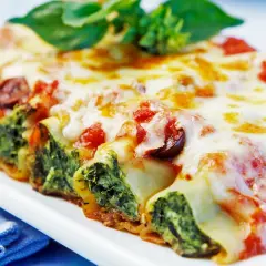 Cannelloni gefüllt mit Spinat und Ricotta, überbacken mit Tomatensauce und Käse, garniert mit Basilikum.