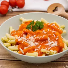 Schüssel mit Pasta und einer leuchtend roten, cremigen Sauce, die an ein traditionelles Tomatensauce Rezept erinnert. Mit Parmesan bestreut und Petersilie garniert.