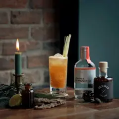 Ein erfrischender Kaffee Cocktail mit Wodka und Cold Brew, garniert mit Zitronengras. Kerzenlicht und Tannenzweige schaffen eine gemütliche Atmosphäre.