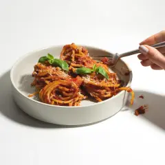 Ein Teller mit Spaghetti, garniert mit Basilikum und Parmesan. Verschiedene Nudel-Sorten sind hier als köstliche Mahlzeit präsentiert.