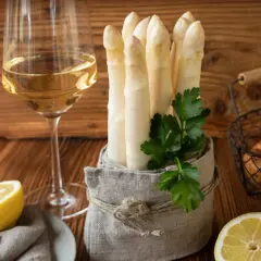 Ein Glas Weißwein neben frischem Spargel, Kartoffeln und Zitronen. Die perfekte Kombination, um die Frage zu beantworten: welchen Wein zu Spargel.