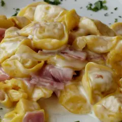 Cremige Tortellini mit Schinken in einer hellen Sauce, garniert mit Petersilie. Perfekt zum Tortellini einfrieren für später.