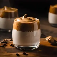 Drei Gläser mit cremigem Kaffee und Kondensmilch, garniert mit Kaffeebohnen.