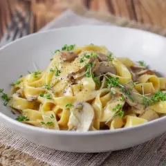 Cremige Tagliatelle mit Pilzen, garniert mit frischen Kräutern und schwarzem Pfeffer. Ein köstliches Gericht, das Lust auf mehr macht.