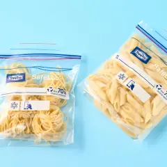 Zwei Zip-Beutel mit Nudeln, bereit zum Einfrieren. Einer enthält Spaghetti, der andere Penne.