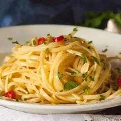Ein Teller Spaghetti aglio olio e peperoncino, garniert mit Petersilie und roten Chilistückchen.