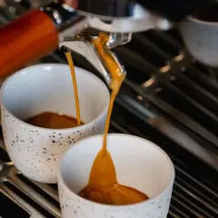 Frisch gebrühter Espresso fließt in zwei Tassen. Hoffentlich ist er nicht zu bitter.