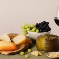 Käseplatte mit Trauben und Rotwein. Die ideale **Primitivo Trinktemperatur** wird durch die kühle Präsentation unterstrichen.