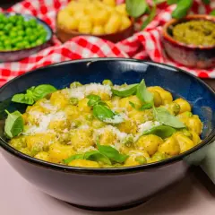 Gnocchi mit Erbsen und Parmesan in cremiger Pesto-Sauce, garniert mit frischem Basilikum.
