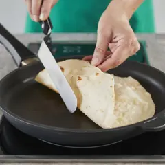 Hände falten Piadinas in einer Pfanne für ein einfaches Piadina Rezept.