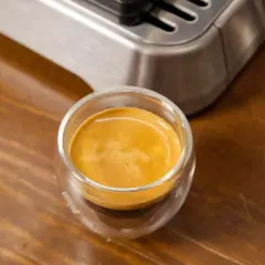 Ein frisch gebrühter Espresso Freddo in einem Glas auf Holztisch.