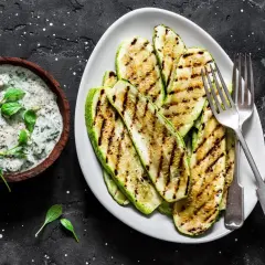 Gegrillte Zucchinischeiben mit Kräuterquark. Perfekt zum **Zucchini zubereiten** für einen leichten Genuss.