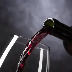 Rotwein fließt aus einer Flasche in ein Glas. Ist Wein vegan? Ja, dieser Wein ist vegan.