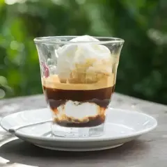Ein Glas mit Espresso und Vanilleeis, das auf einem Tisch im Freien steht.