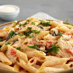 Cremige Penne mit sonnengetrockneten Tomaten, Spinat und Parmesan, garniert mit frischer Petersilie. Ein köstliches Gericht, das Lust auf mehr macht.