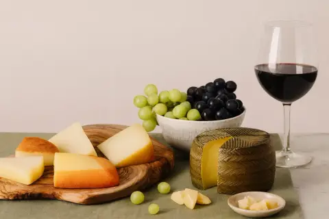 Käseplatte mit Trauben und Rotwein. Die ideale **Primitivo Trinktemperatur** wird durch die kühle Präsentation unterstrichen.