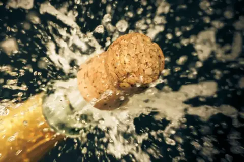 Champagnerkorken spritzt aus der Flasche, ein Moment des Feierns, der zeigt, wie wichtig es ist, Champagner richtig zu lagern.