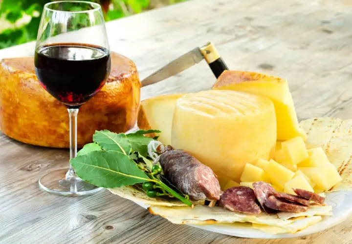 Ein Glas Rotwein, passend zu Käse und Salami. Der Wein könnte aus der Nebbiolo Traube stammen.