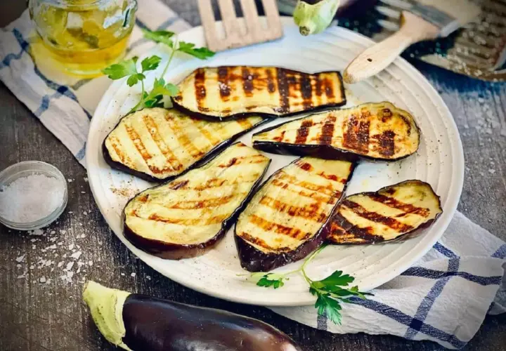 Gegrillte Aubergine-Scheiben mit Grillstreifen, garniert mit Petersilie, daneben Salz und Öl.