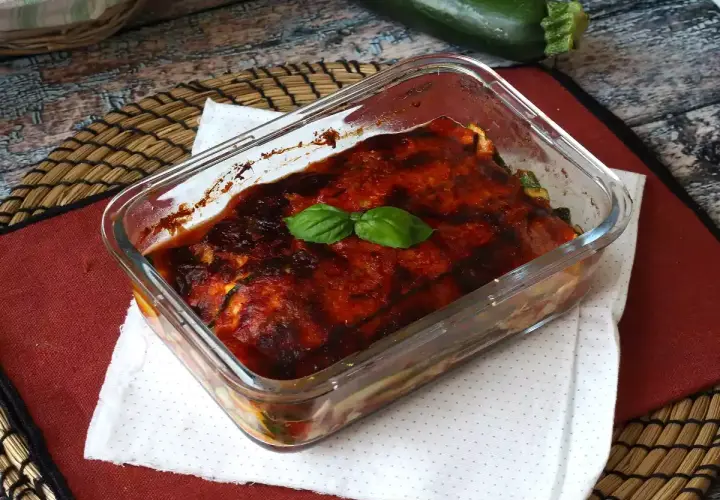 Herzhaftes Zucchini Piccata im Glasauflauf, mit Tomatensauce und Basilikum garniert.