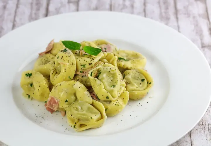 Spinat Ricotta Tortellini in cremiger Sauce, garniert mit Basilikum und schwarzem Pfeffer. Ein köstliches Gericht, das zum Genießen einlädt.