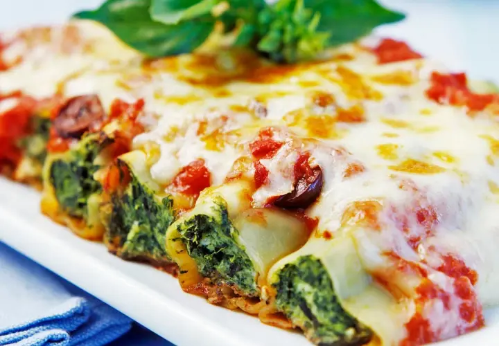 Cannelloni gefüllt mit Spinat und Ricotta, überbacken mit Tomatensauce und Käse, garniert mit Basilikum.