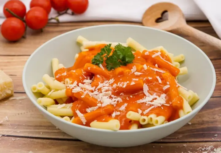 Schüssel mit Pasta und einer leuchtend roten, cremigen Sauce, die an ein traditionelles Tomatensauce Rezept erinnert. Mit Parmesan bestreut und Petersilie garniert.