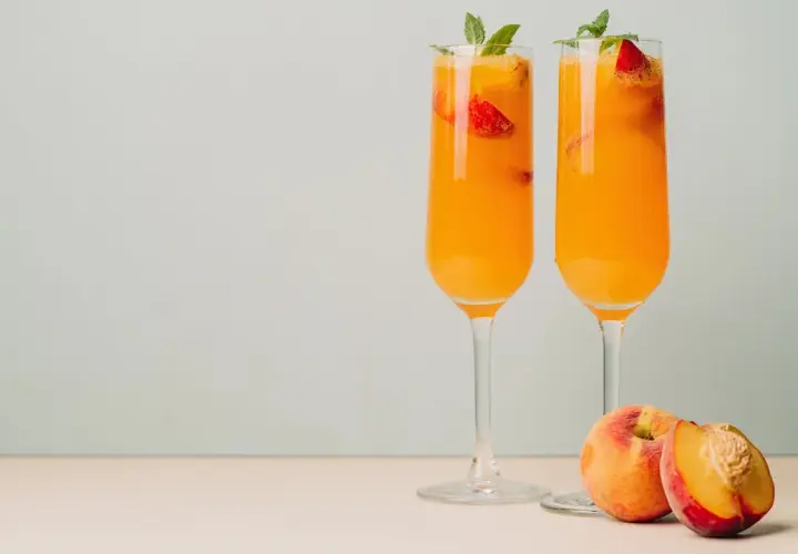 Zwei Bellini-Cocktails mit Pfirsich und Erdbeeren, garniert mit Minze. Das Bellini Rezept original ist einfach und erfrischend.