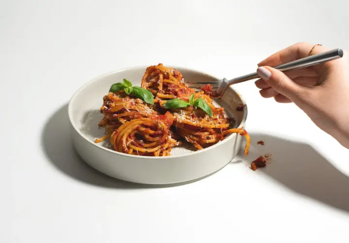 Ein Teller mit Spaghetti, garniert mit Basilikum und Parmesan. Verschiedene Nudel-Sorten sind hier als köstliche Mahlzeit präsentiert.