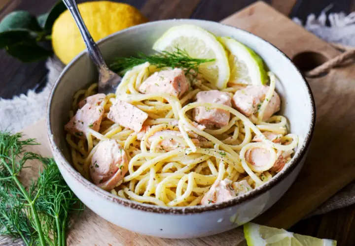 Eine Schüssel Pasta mit Lachs, garniert mit Dill und Zitronenscheiben. Ein köstliches Pasta Salmone Gericht.