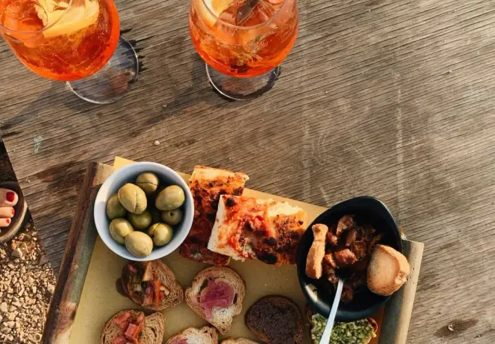 Zwei Aperol Spritz und eine Auswahl an italienischen Aperitif-Spezialitäten: Oliven, Bruschetta und Pizza.