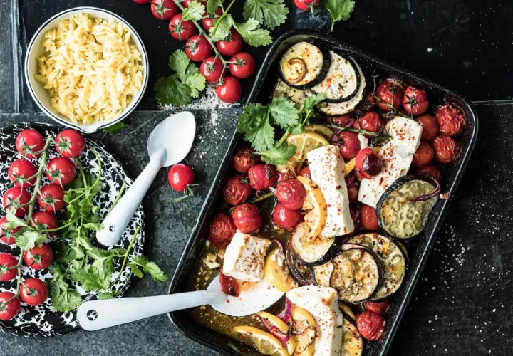 Ofenfrisches Gericht mit Aubergine, Tomaten und Feta. Dazu Orzo-Nudeln und frische Kräuter.