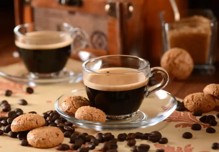 Zwei Tassen italienische Kaffeesorten mit Amarettini und Kaffeebohnen.
