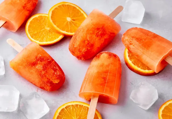 Erfrischendes Aperol Spritz Eis mit Orangenscheiben und Eiswürfeln. Perfekt für heiße Sommertage.