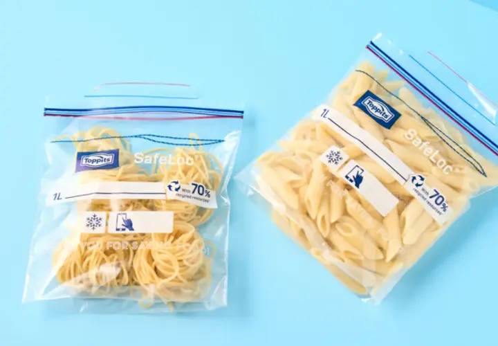 Zwei Zip-Beutel mit Nudeln, bereit zum Einfrieren. Einer enthält Spaghetti, der andere Penne.