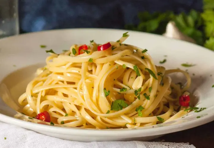 Ein Teller Spaghetti aglio olio e peperoncino, garniert mit Petersilie und roten Chilistückchen.