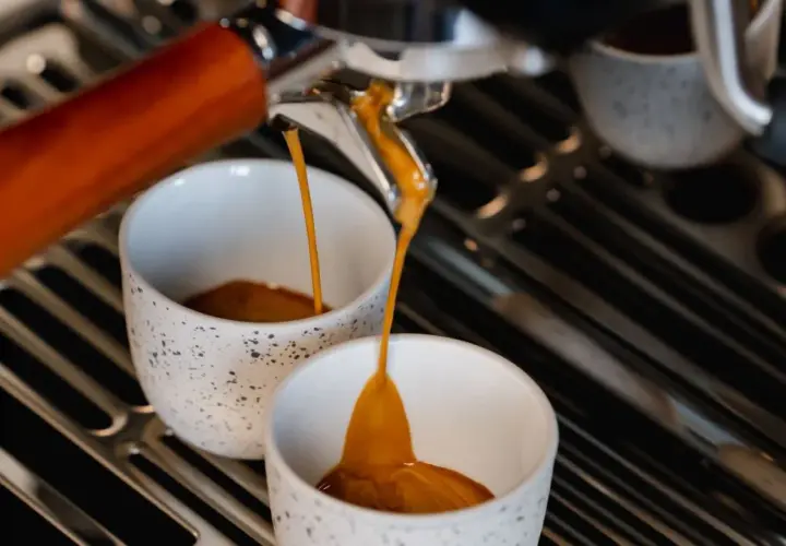 Frisch gebrühter Espresso fließt in zwei Tassen. Hoffentlich ist er nicht zu bitter.