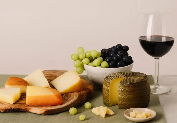 Käseplatte mit Trauben und Rotwein. Die ideale **Primitivo Trinktemperatur** wird durch die kühle Präsentation unterstrichen.