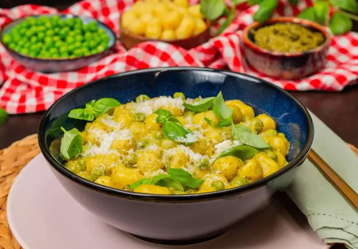 Gnocchi mit Erbsen und Parmesan in cremiger Pesto-Sauce, garniert mit frischem Basilikum.