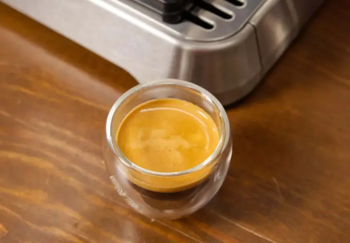 Ein frisch gebrühter Espresso Freddo in einem Glas auf Holztisch.