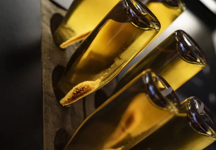 Flaschen mit Hefeablagerungen im Rüttelpult, ein Zeichen für die traditionelle Methode Champenoise.