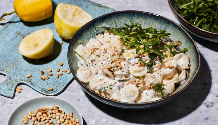 Cremige Ricotta Zitronen Pasta mit Pinienkernen und Rucola, garniert mit frischer Zitronenschale.
