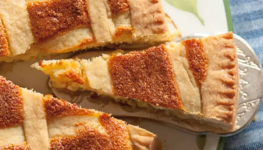 Ein Stück Pastiera Napoletana, ein traditioneller italienischer Kuchen, mit Gittermuster. Das Rezept ist einfach und das Ergebnis köstlich.