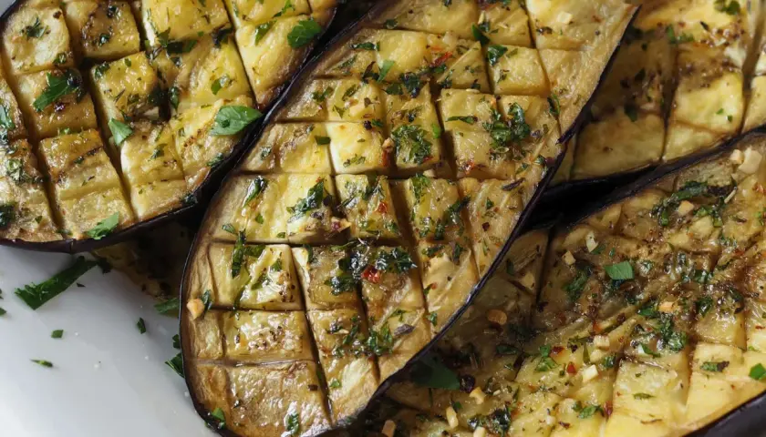 Ganze Aubergine im Ofen, in Scheiben geschnitten und mit Kräutern und Gewürzen verfeinert, bereit zum Genuss.